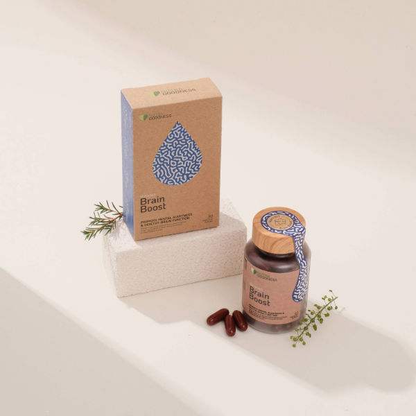 A bottle and box of brain booster supplements Singapore, presented on a minimalist white platform with small herbal sprigs, showcasing natural packaging and capsule form.